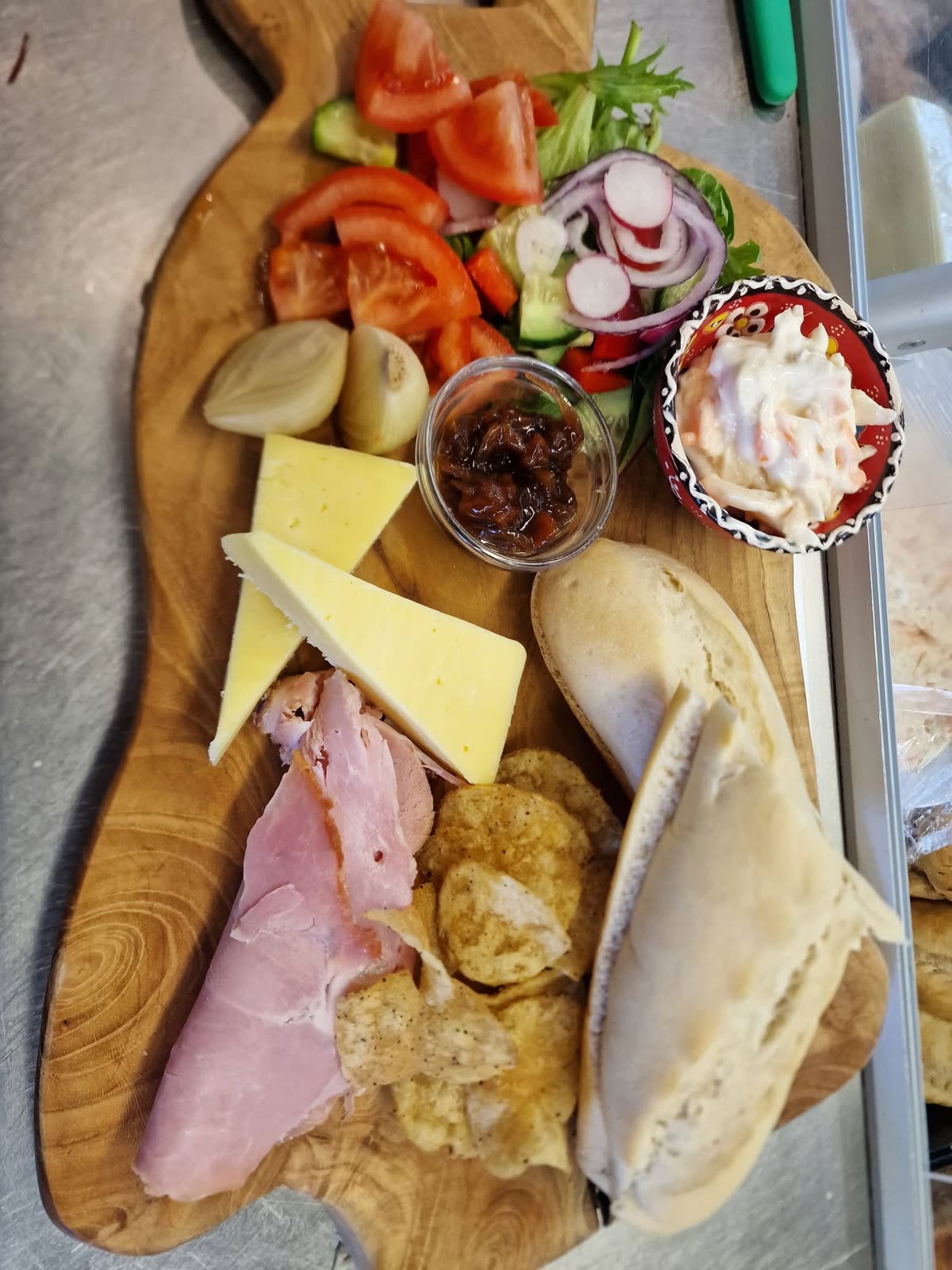 A ploughman's board with ham, cheese, bread, pickle and tomatoes